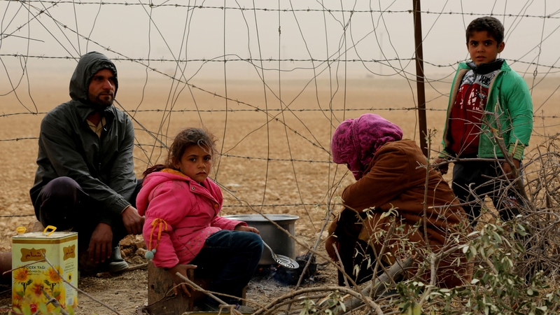 A Syrian woman cooks food for her family members at a temporary refugee camp in the village of Ain Issa