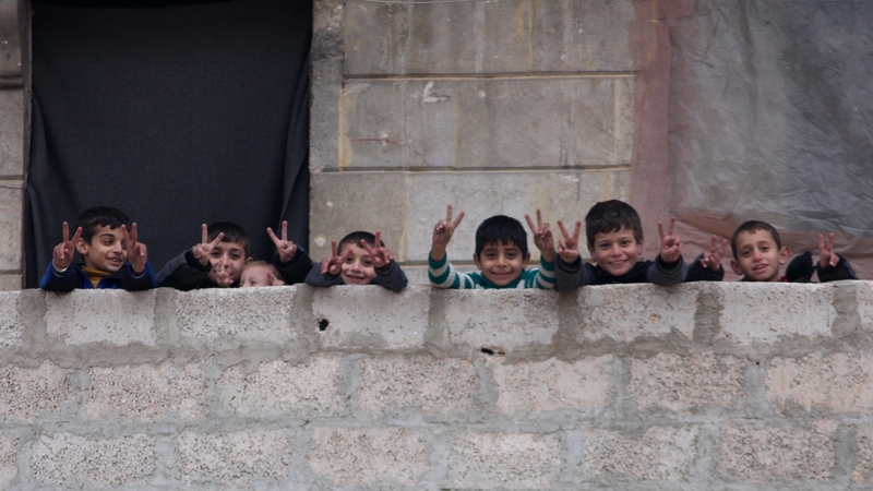 Children flash the victory sign from one of the houses in Salah al-Din neighbourhood, east of Aleppo yesterday
