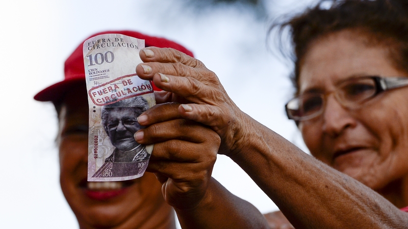 Supporters of President Maduro hold 100-Bolivar notes with the face of the president of the National Assembly