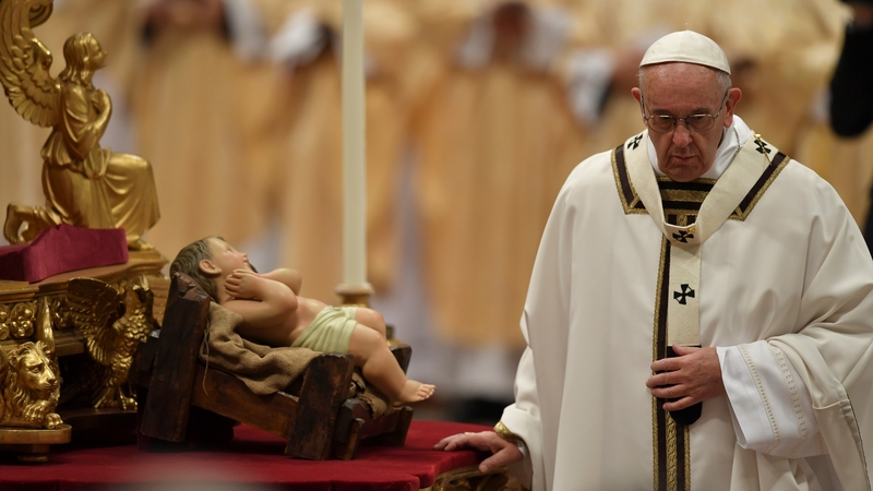Pope Francis stands flanked a figurine of baby Jesus as he celebrates a mass on Christmas Eve