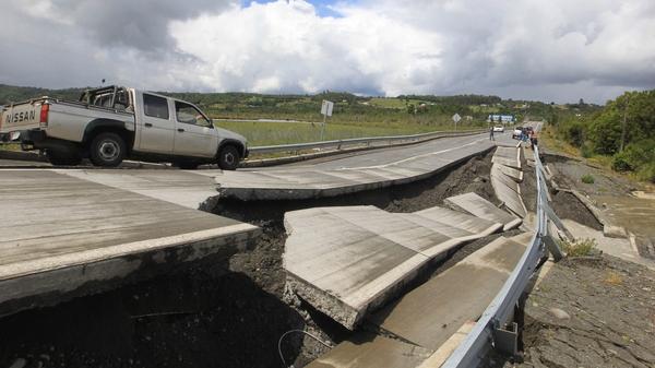 A truck drives by next to damage caused on a highway on Chiloe Island off the Pacific coast of southern Chile