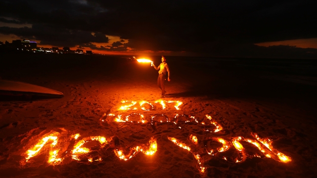 Palestinian artist Osama Sbeata lights the words '2017 Happy New Year' written in the sand in Gaza