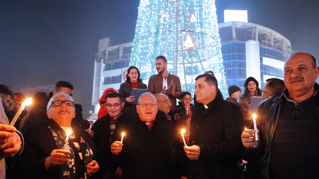 Iraqis gather at the al-Mansour square with Archbishop Louis Sako (C), patriarch of the Catholic Church in Iraq, during Christmas and New Years eve celebrations in Baghdad