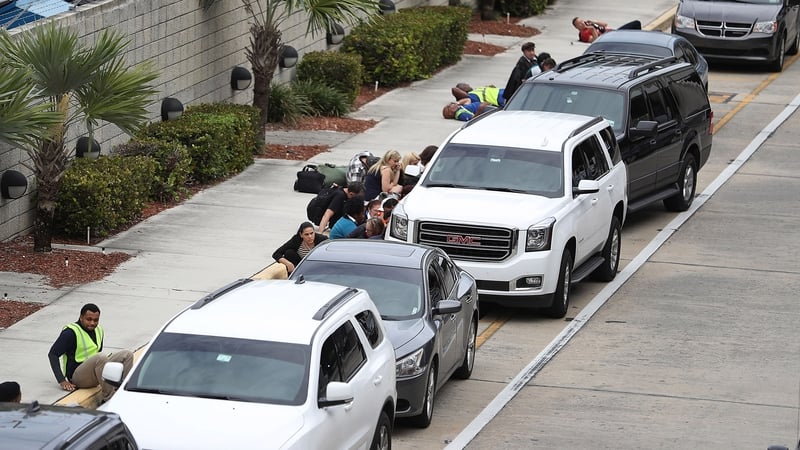 People take cover behind cars outside Terminal 2 at Fort Lauderdale-Hollywood International airport after the shooting