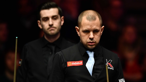 Barry Hawkins considers a shot as Mark Selby looks on
