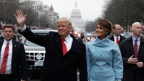 US President Donald Trump waves as he walks with US First Lady Melania Trump during the inauguration parade in Washington