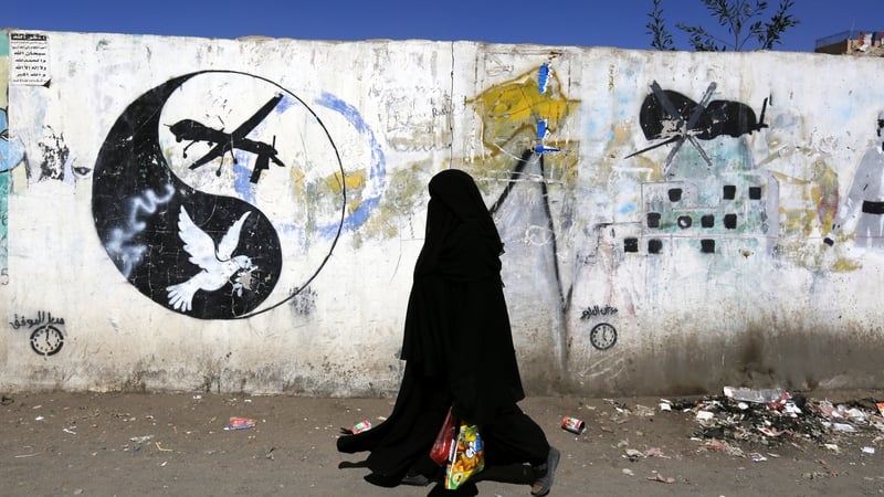 A woman walks past graffiti protesting US operations in war-affected Yemen