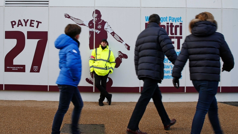 A security guard protects an image of Dimitri Payet outside West Ham's London Stadium