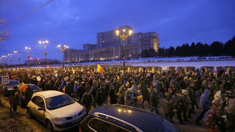 Romanian people gather to form a human chain around the parliament building (background) after a protest march in Bucharest today