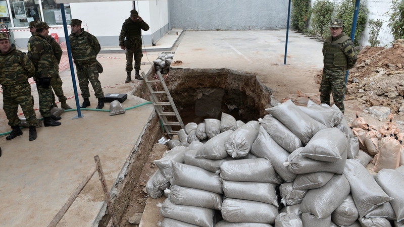 Military personnel stand at the site of a World War II bomb in Thessaloniki
