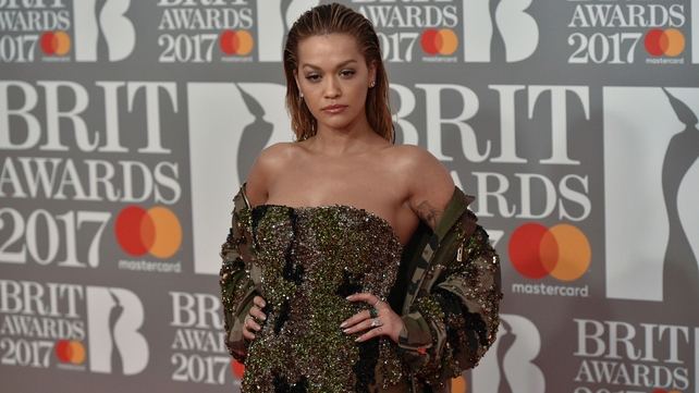 Rita Ora is not nominated for any Brit Awards this year but donned an opulent glittering green gown with a corset-style top half leading into a sheer full skirt for the occasion