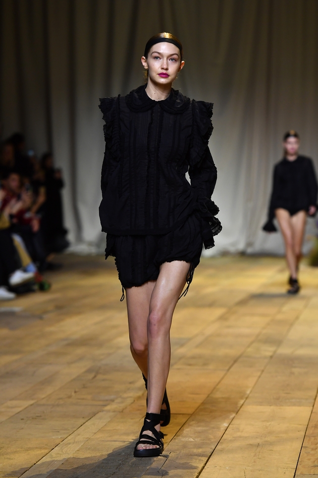 Gigi Hadid looking lovely in froufrous and fuchsia lipstick at the H&M Studio Fashion Show.