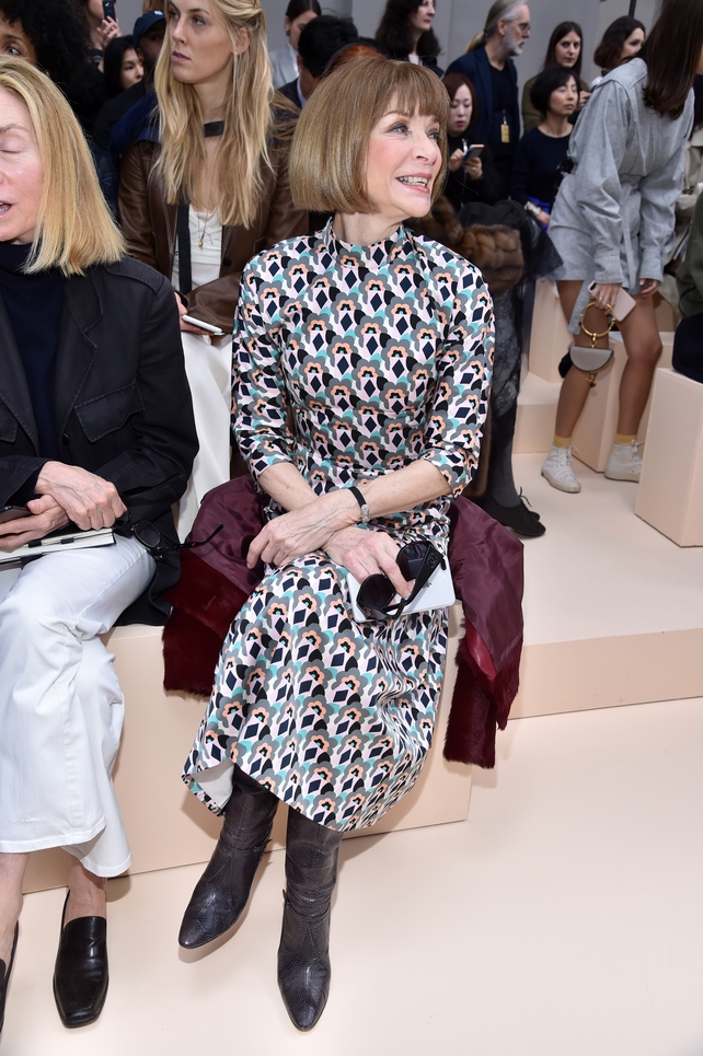 A cheerful Anna Wintour in an iconic dress and boots combo at the Chloé Fashion Show.