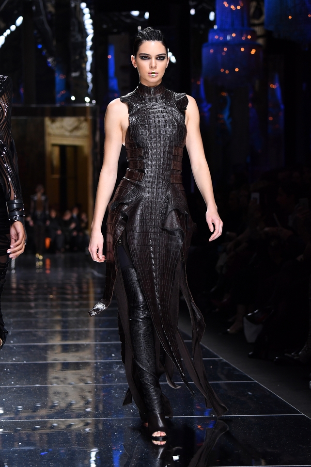 Kendall Jenner walks the Balmain Fashion Show in all black and gold lips.