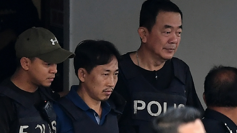 Ri Jong Chol (C) is escorted with a heavy police presence as he leaves the Sepang police headquaters