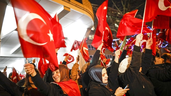 People wave Turkish flags as they protest outside the Turkish consulate in Rotterdam