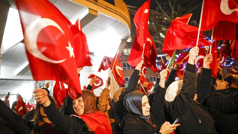 People wave Turkish flags as they protest outside the Turkish consulate in Rotterdam