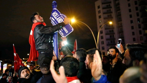 Protesters tear down a sign outside the Dutch embassy in Ankara