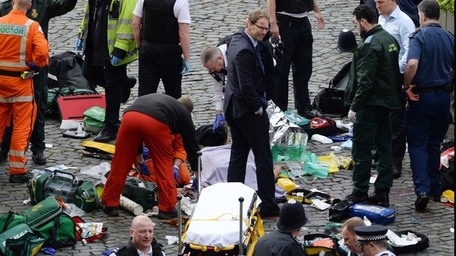 Conservative MP Tobias Ellwood stands among emergency services outside the UK Parliament in Westminster