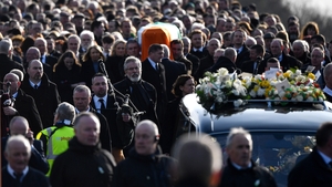 Gerry Adams walks with the funeral cortege as it leaves St Columba's Church and makes its way to the City Cemetery