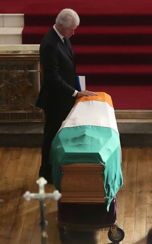 Bill Clinton touches the coffin during the funeral of Martin McGuinness