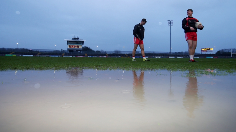 Players walk around one of the large puddles at Healy Park after the game was called off.