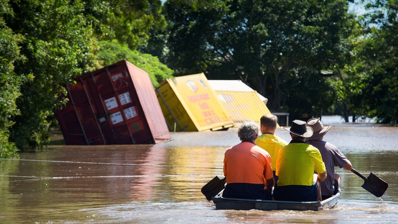 People paddle through flood water in Beenleigh, Queensland