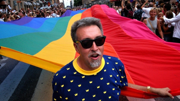 Gilbert Baker with the iconic rainbow coloured flag on a march in 2003