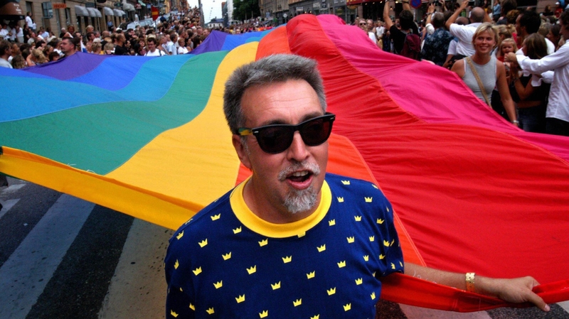 Gilbert Baker with the iconic rainbow coloured flag on a march in 2003