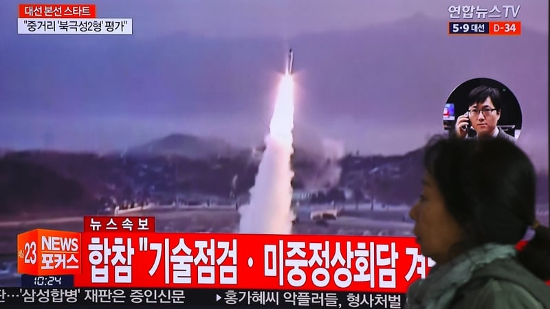 A woman walks past a television screen showing file footage of a North Korean missile launch, at a railway station in Seoul