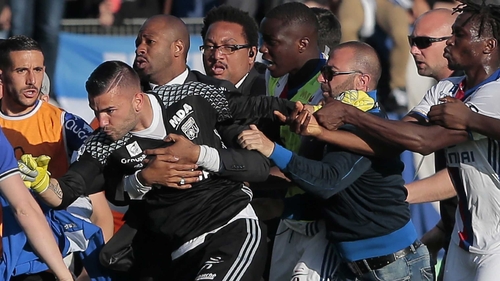 Security staff holds Lyon's goalkeeper Anthony Lopes (C) during scuffles at half-time