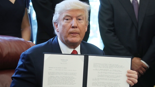 US President Donald Trump holds up his executive memorandum on the investigation of steel imports