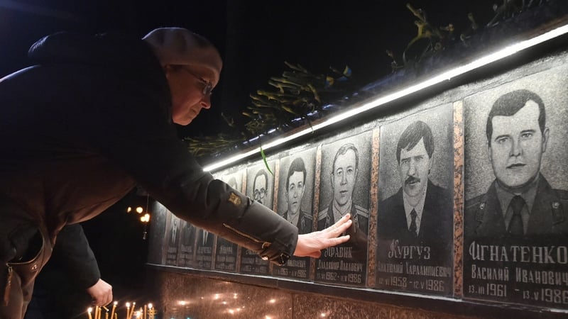 A woman touches a portrait during a memorial ceremony at the monument to Chernobyl victims in Slavutich