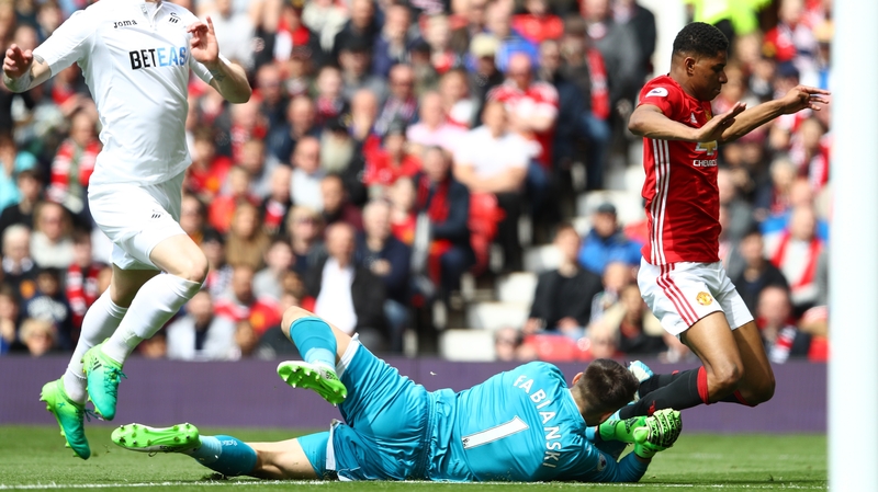 Manchester United's Marcus Rashford falls as Swansea keeper Lukasz Fabianski dives near his feet