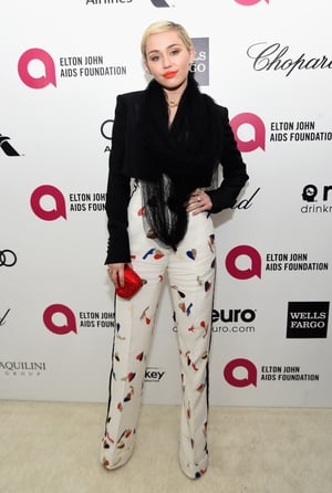 Miley attended the Elton John AIDS Foundation Academy Awards Viewing Party in 2015. Her patterned high waist trousers and Judith Leiber heart clutch are lovely!