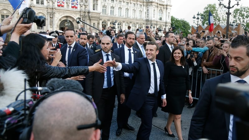 French President Emmanuel Macron (centre) greets the crowds as he walks with Paris Mayor Anne Hidalgo after the ceremony