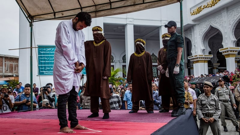 The men stood quietly, their heads down, as spectators heckled them and shouted insults