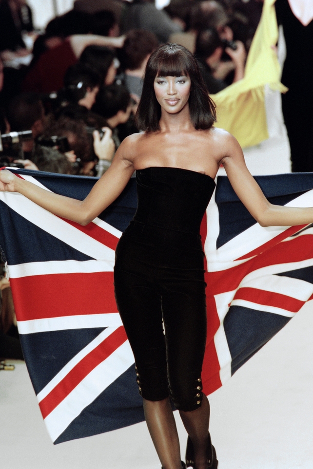 Back in her 90's glory! The British model holds her flag during a Chanel fashion show in 1994.