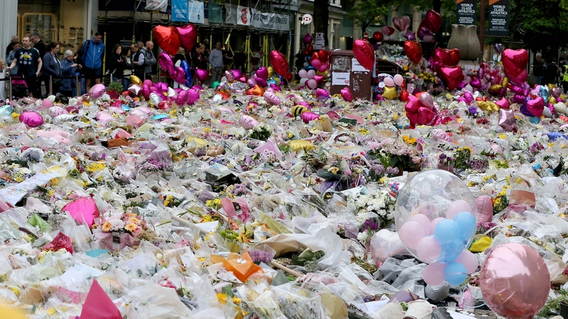 People lay flowers at a memorial for the victims at St Ann's Square, near Manchester Arena