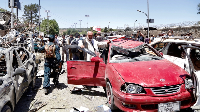 Afghan security officials inspect the scene of the suicide bomb attack in Kabul