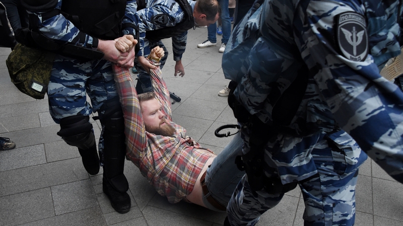 Russian police officers detain a protester at the opposition rally in central Moscow