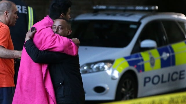 Two men embrace within the security cordon at the Grenfell Tower block blaze