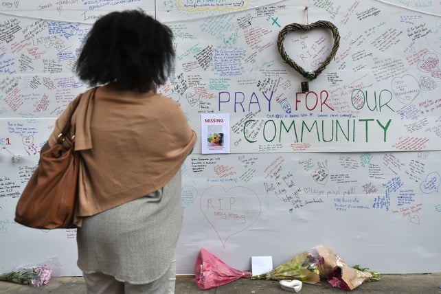 A woman views a tribute wall near the Grenfell Tower