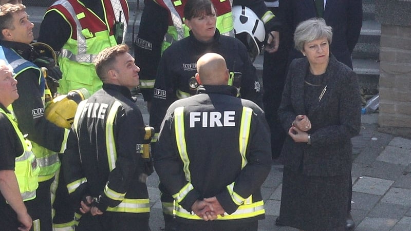 Theresa May speaks to fire fighters while visiting the site of the Grenfell Tower fire