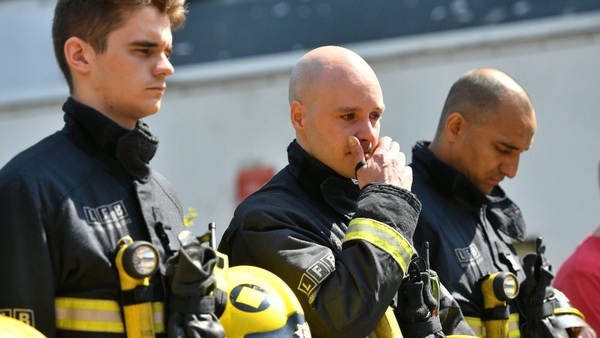 Firefighters pause to observe a minute's silence at the scene