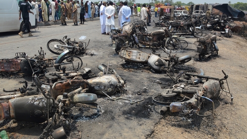 Soldiers stand guard beside burnt out vehicles at the scene where an oil tanker caught fire following an accident on a highway