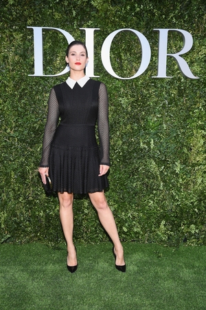 Gemma Arterton attends 'Christian Dior, couturier du reve' in a simple black dress with fishnet sleeves and sharp white collar.