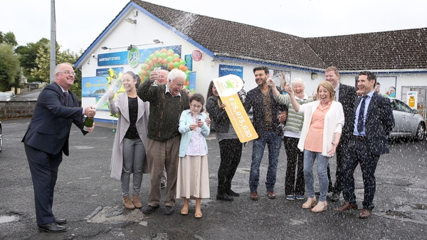 Locals and shop workers celebrate outside the Gala store where the winning ticket was sold