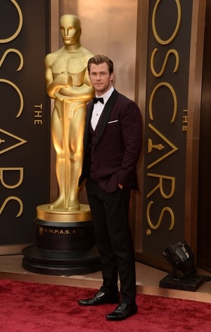 This David August burgundy tuxedo enhances Chris Hemsworth charm at the Oscars ceremony in 2014.