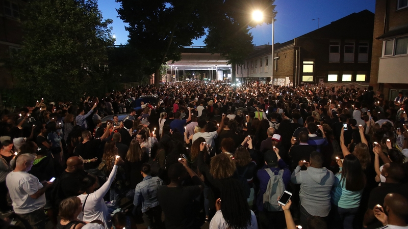 People attend a vigil to mark four weeks since the Grenfell Tower fire, at the memorial wall on Bramley Road, London